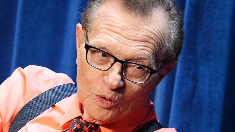 Larry King leaning over orange shirt