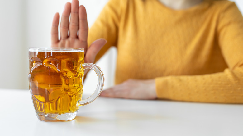 Woman orange sweater pushing away glass of beer