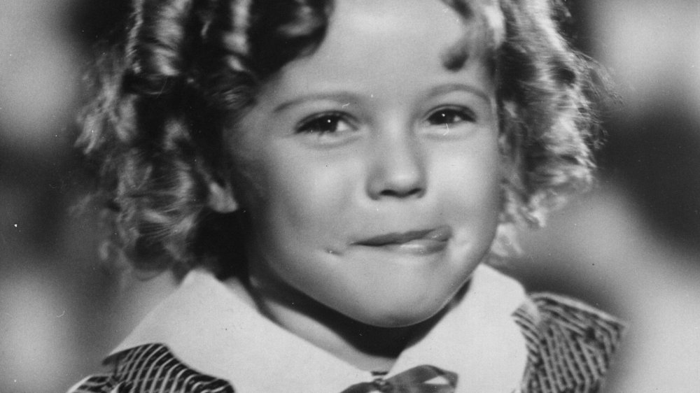 Shirley Temple (1928 - ) the American child star at five years of age, standing on her climbing frame at home.