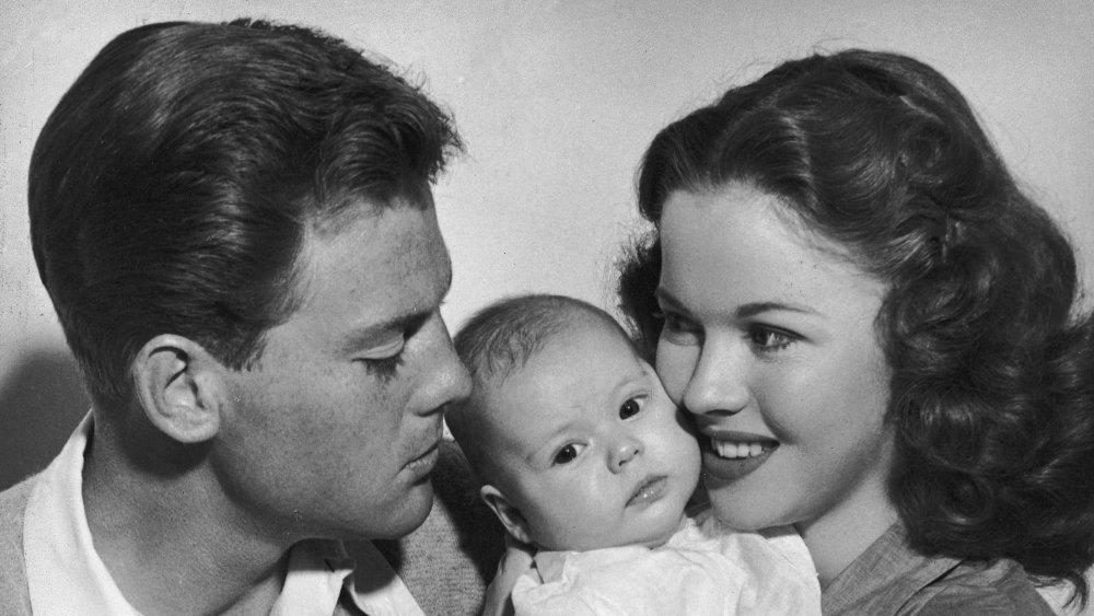 Shirley Temple and John Agar (1921 - 2002) pose with their three-month-old baby daughter,