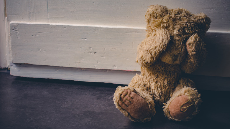 Abandoned Teddy Covering His Eyes, Sitting At A Door - Child Abuse Concept