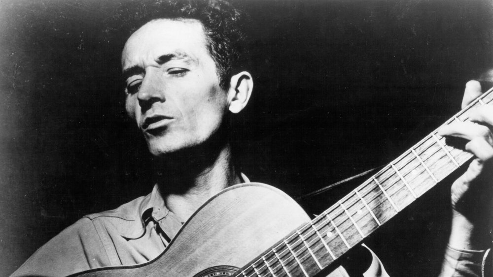 Woody Guthrie holding a guitar