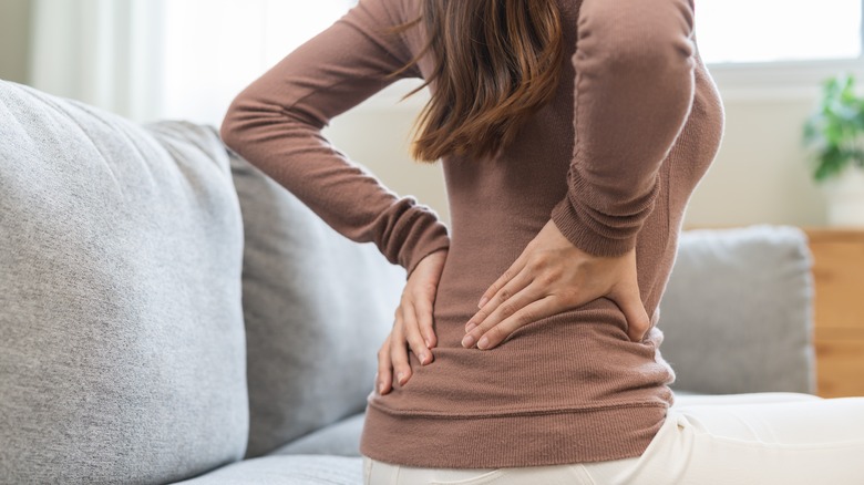 Person on couch massaging their back