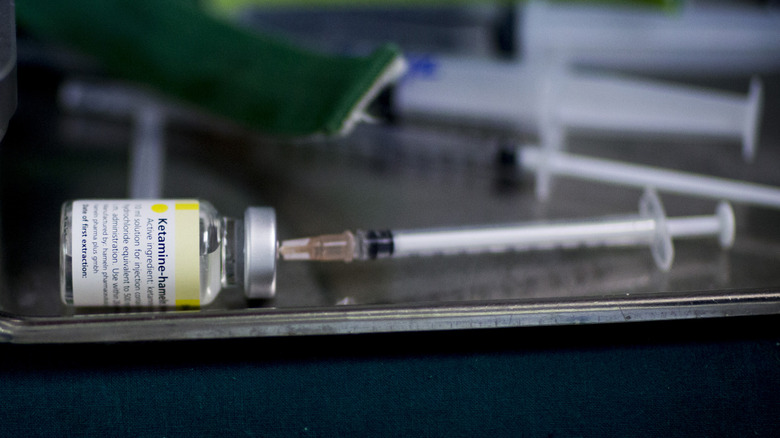 A syringe draws from a vial of ketamine