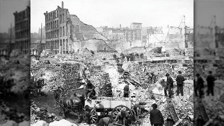 people standing on debris of burned building