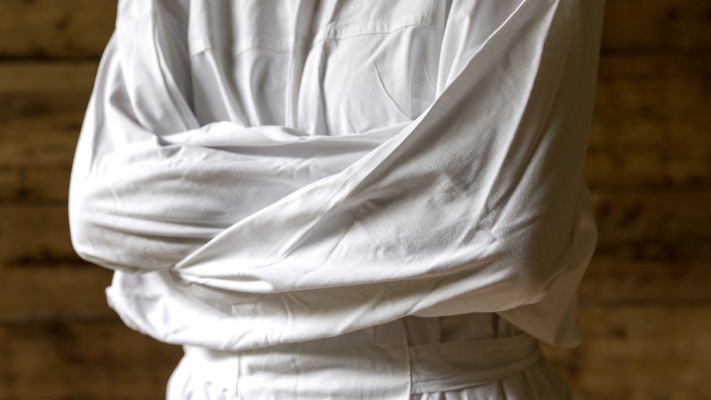 Person in straitjacket, dark background