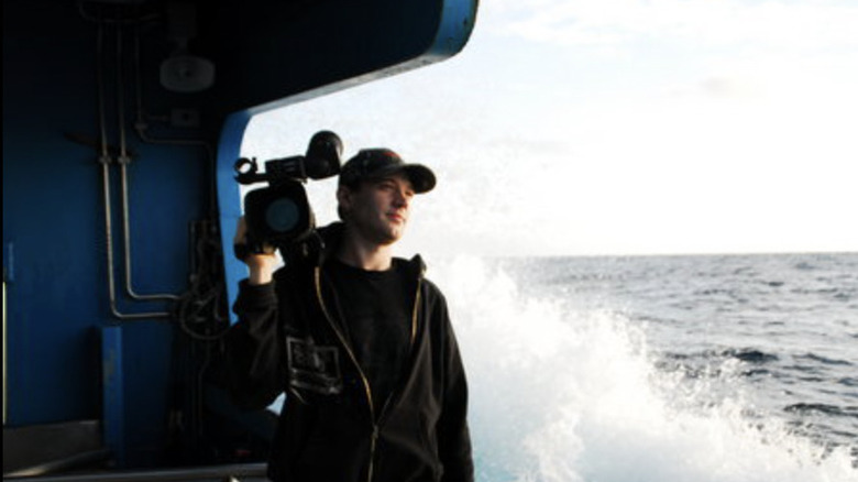 Lee Grivas on boat with camera