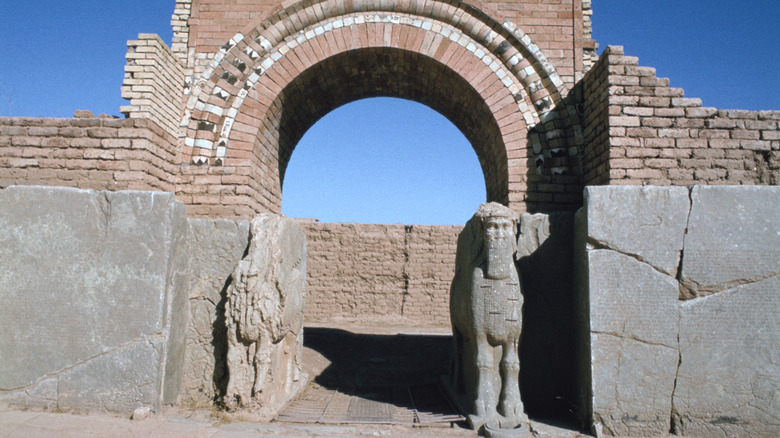 ancient brick gate flanked by broken statues 