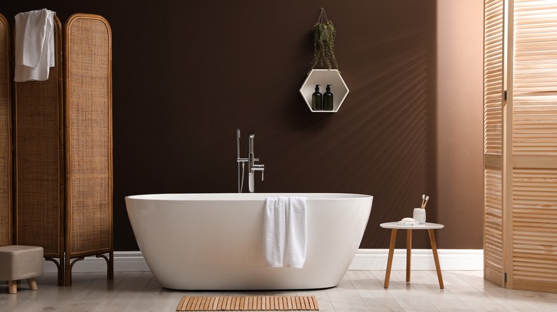 bathtub in room with brown walls