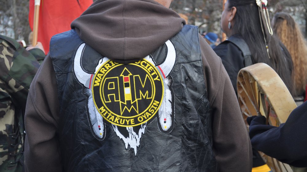 A member of the Warrior Society Mitakuye Oyasin wears an AIM jacket at the raising of the John T. Williams Memorial Totem Pole, Seattle Center