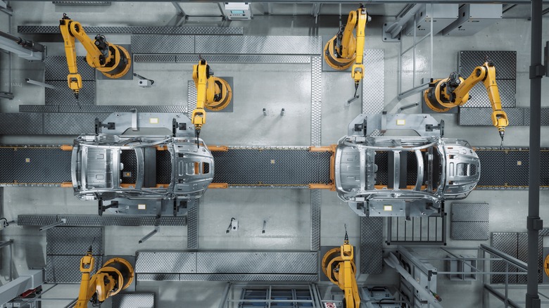 Aerial view of car factory robot arms assembling cars