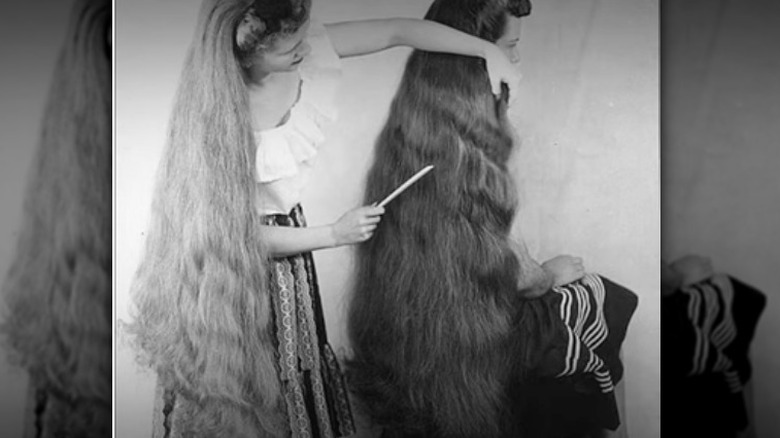 Image of woman with long hair combing hair of another woman