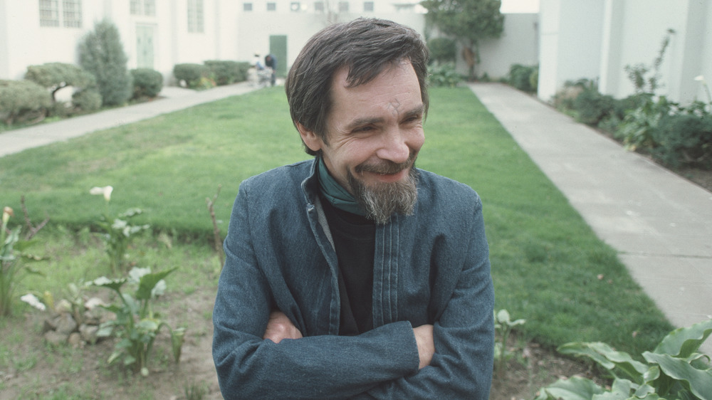 A groomed Charles Manson in prison sitting outside