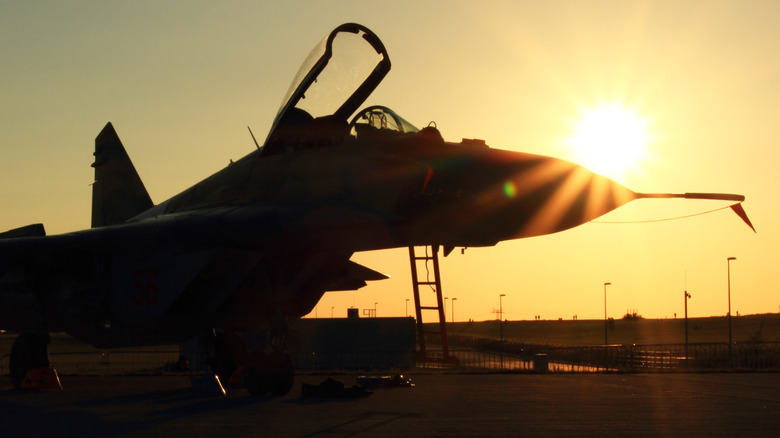 Jet fighter silhouetted against sun