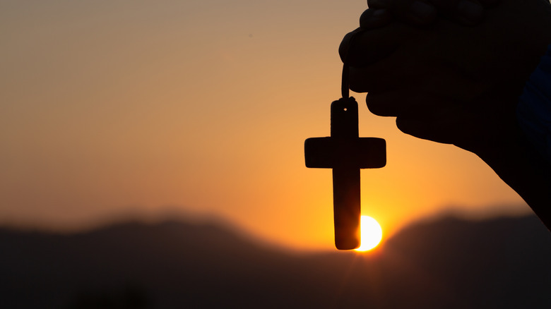 hands holding a cross in silohette