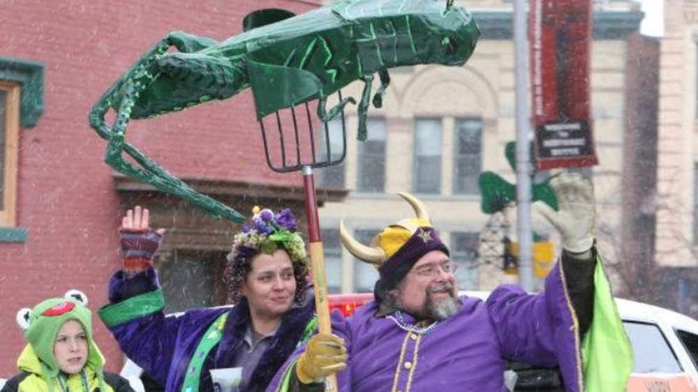 People dressed in purple wearing Viking hats under a grasshopper balloon