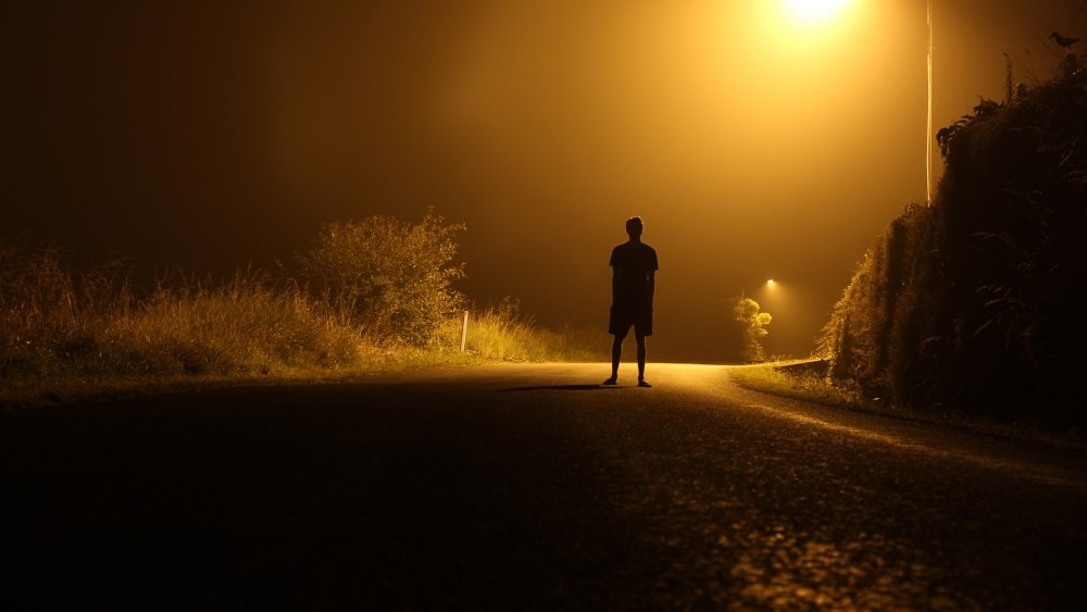 Man alone at night on road.