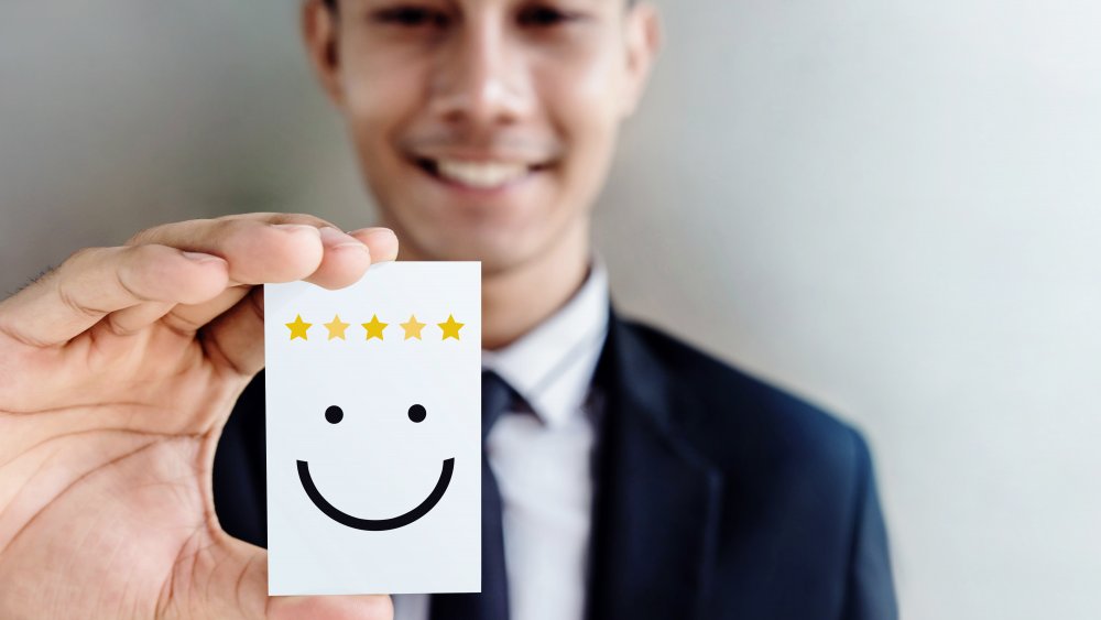 Young man holds smiley face card.