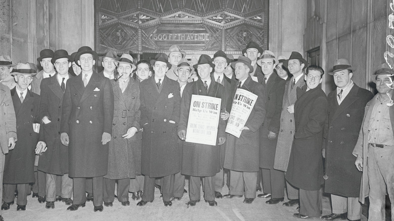 men holding newspaper about elevator operators on strike