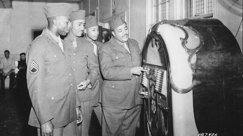 four men in military uniform standing by a jukebox