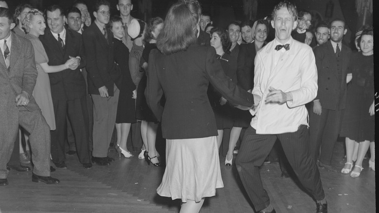 Two people swing dancing among a crowd of people