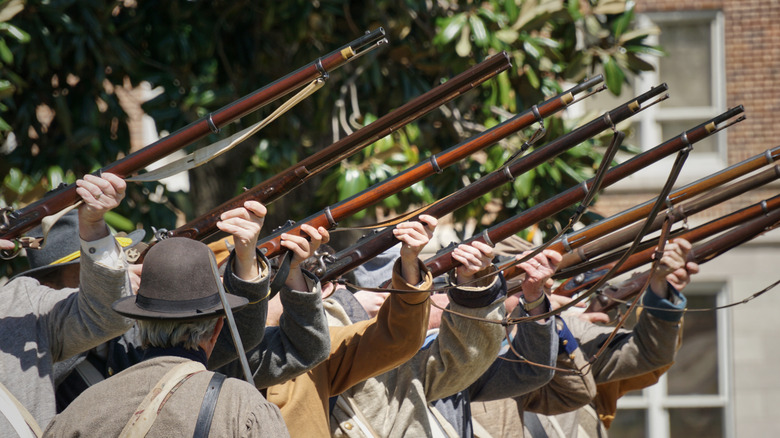 Civil War reenactors raise their muskets