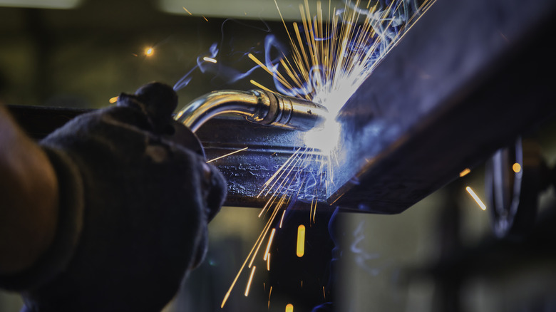 A gloved hand operating a metal welder