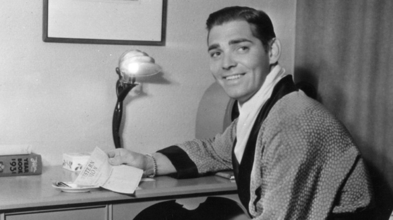 Clark Gable seated at desk, looking away