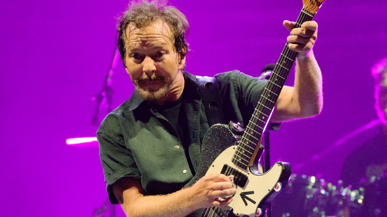 Eddie Vedder holding his guitar up in the air