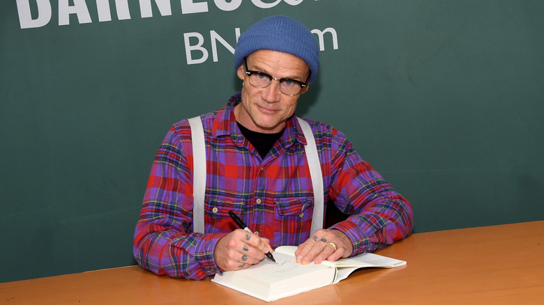 Flea signs a book