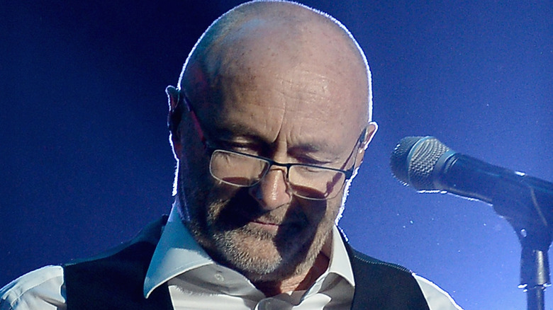 Phil Collins bows head while singing