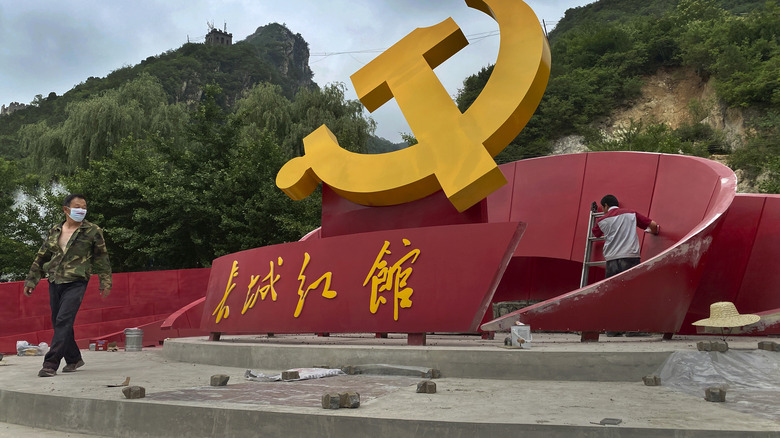 Workers refurbish a monument to the Communist Party of China