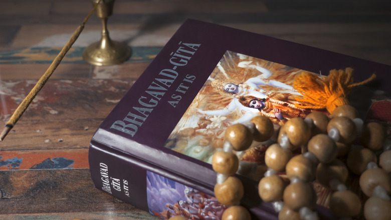 Bhagavad-Gita and rosary beads on wooden surface