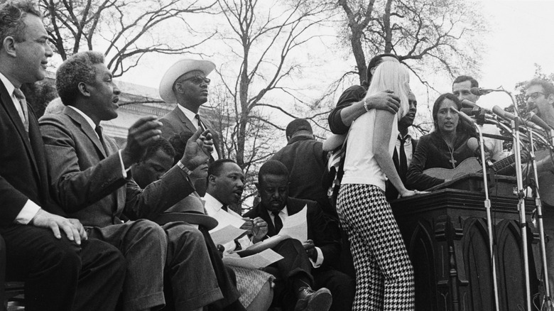 Joan Baez at a podium on stage with MLK Jr.