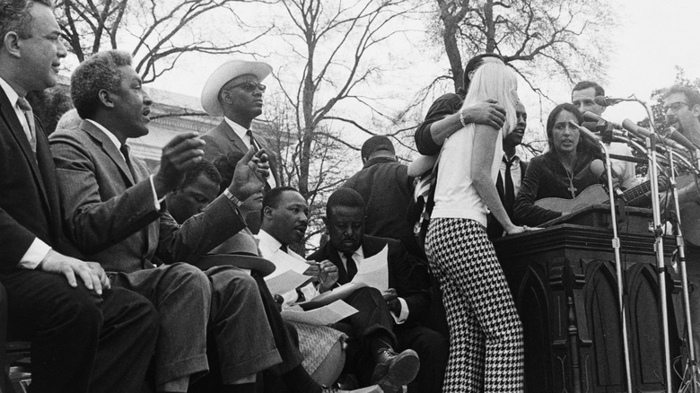 Joan Baez at a podium on stage with MLK Jr.