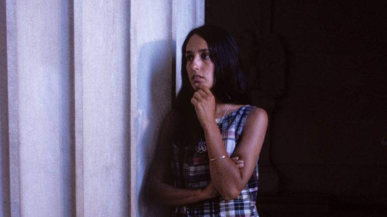 Young Joan Baez posing by a large pillar