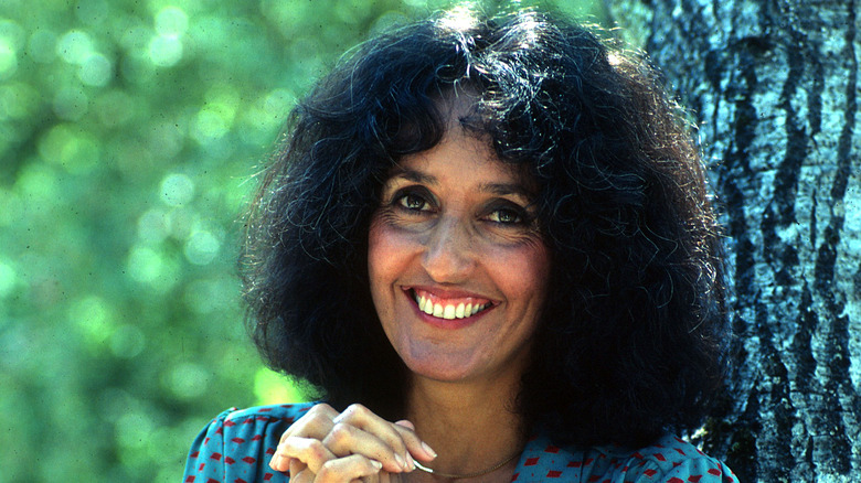 Joan Baez posing with a tree