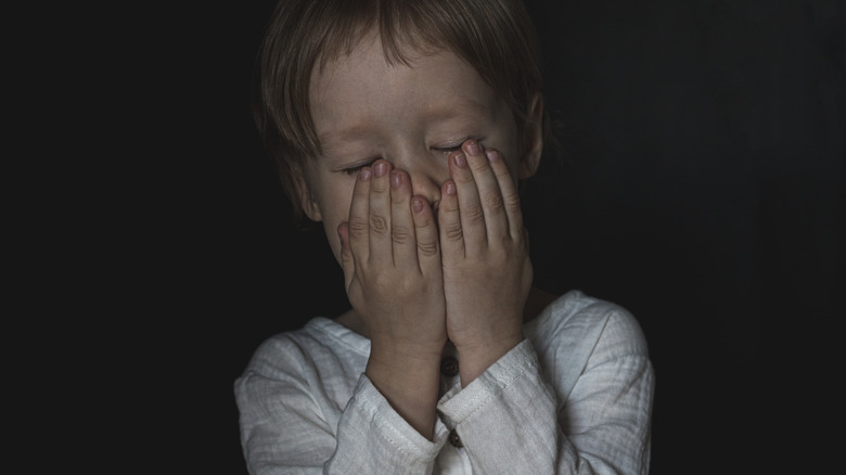 a boy covering his mouth