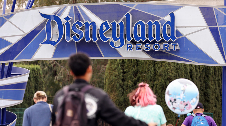 Tourists by a large banner at the entrace to Disneyland