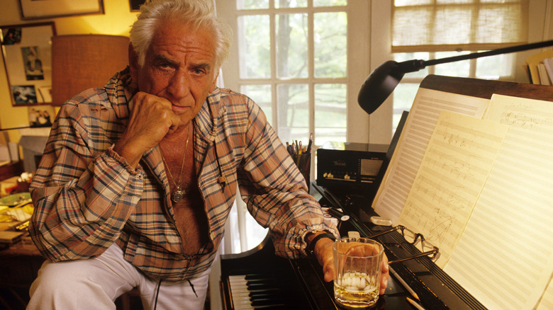 Leonard Bernstein at his piano with drink