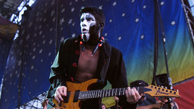 Wes Borland face paint black shirt guitar on stage