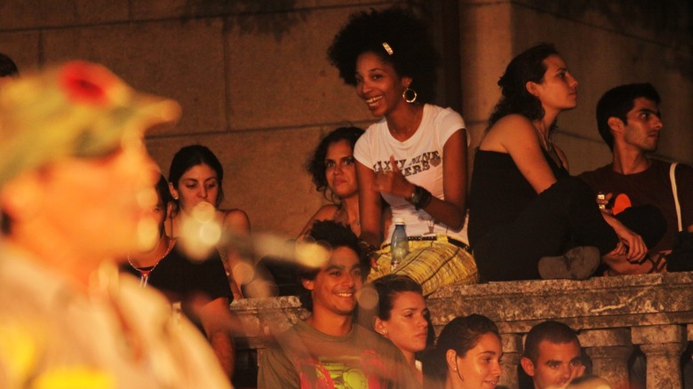 Manu Chao out of focus during a performance while a girl in the background gives a thumbs-up