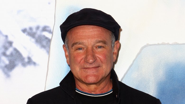 Robin Williams in a black hat in front of a white background