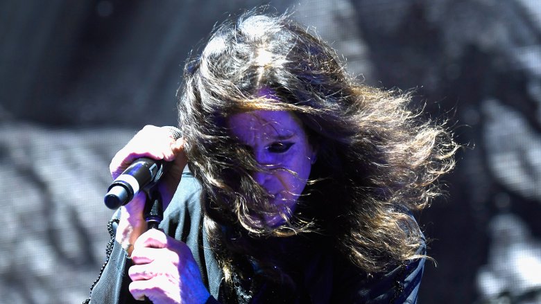 Ozzy Osbourne with his hair in front of his face mid-performance