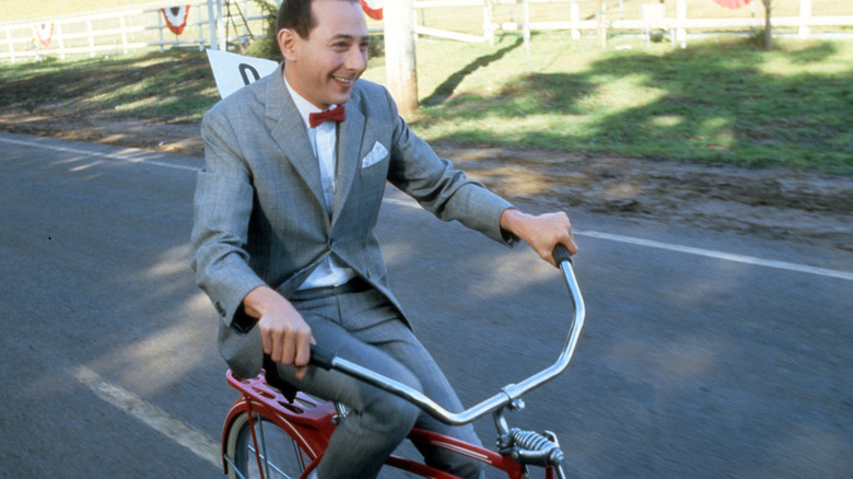 Paul Reubens as Pee-wee Herman riding a bike