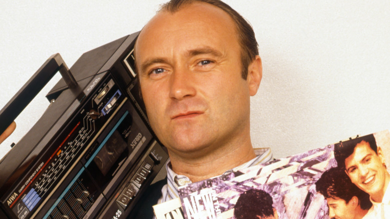 Phil Collins holding records and a boombox