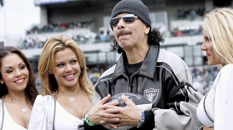 Carlos Santana with Raiders cheerleaders