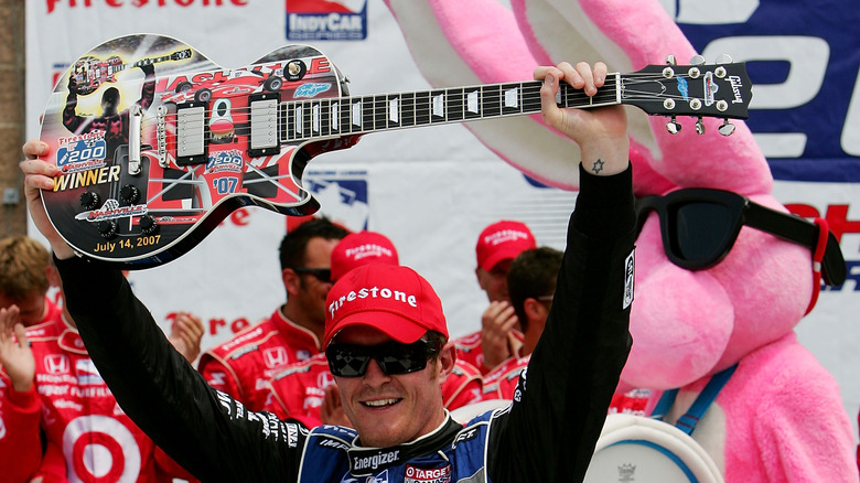 Scott Dixon holds up a guitar