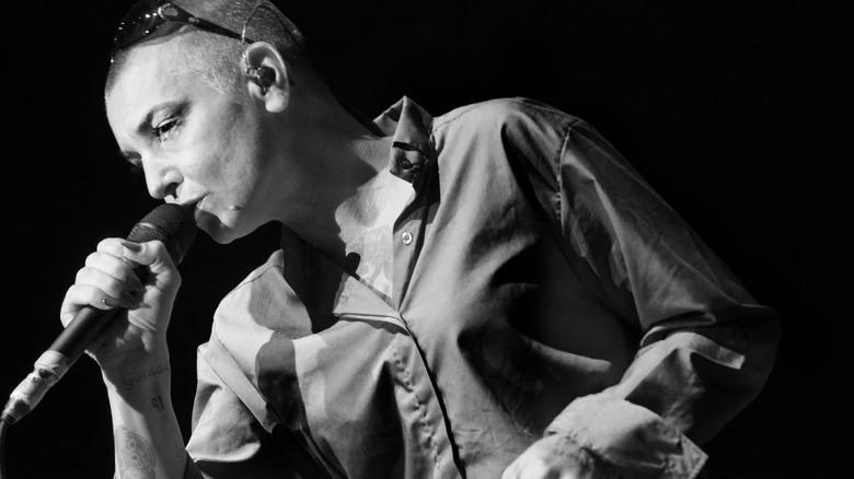 Sinéad O'Connor onstage with mic and sunglasses on head