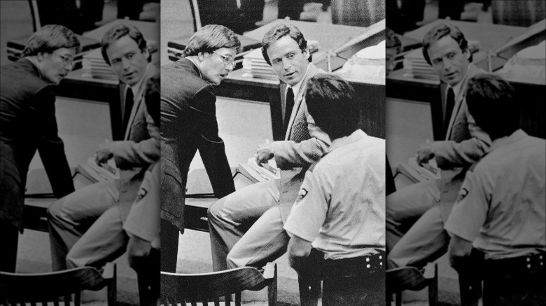 Ted Bundy, sitting on table, talks with assistant public defender in court